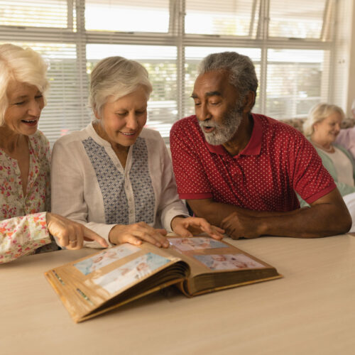 Group of senior people looking at photo album at nursing home