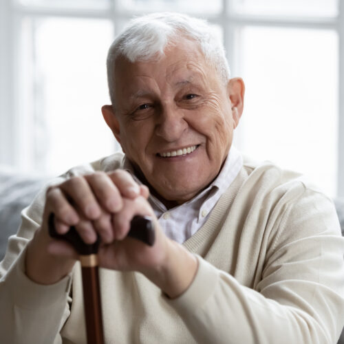 Happy senior grandfather sitting on couch smiling demonstrating healthy teeth